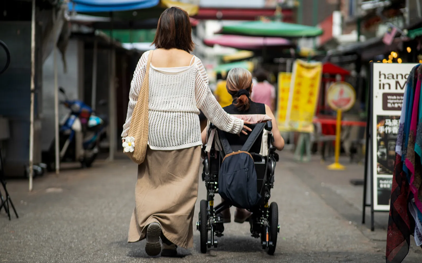 Woman walking and supporting a woman using a wheelchair