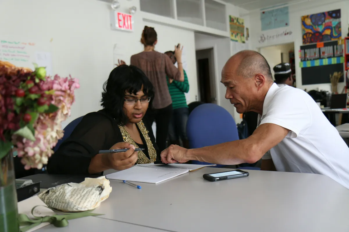 Man helping woman with a notebook