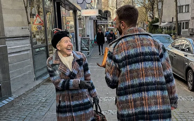 Man and woman smiling at each other when they realize they are wearing the same coat